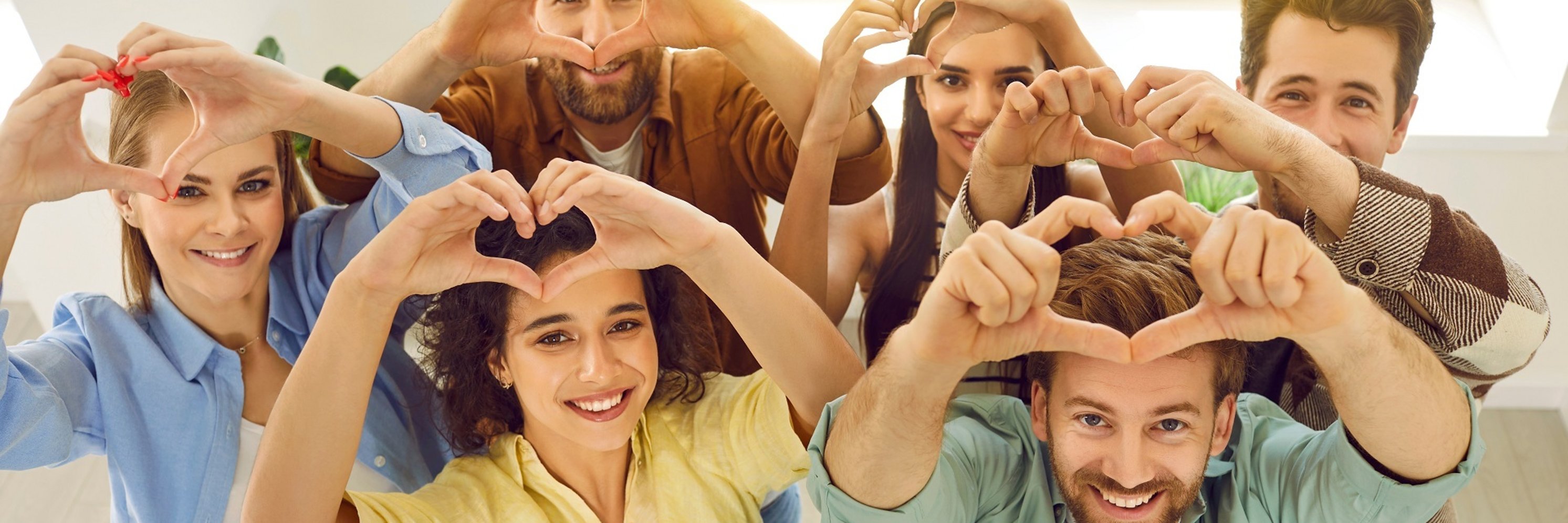 Group of happy young people making hearts with their hands as symbol of love and support