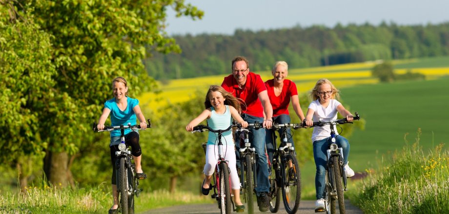 Family with kids cycling in summer with bicycles