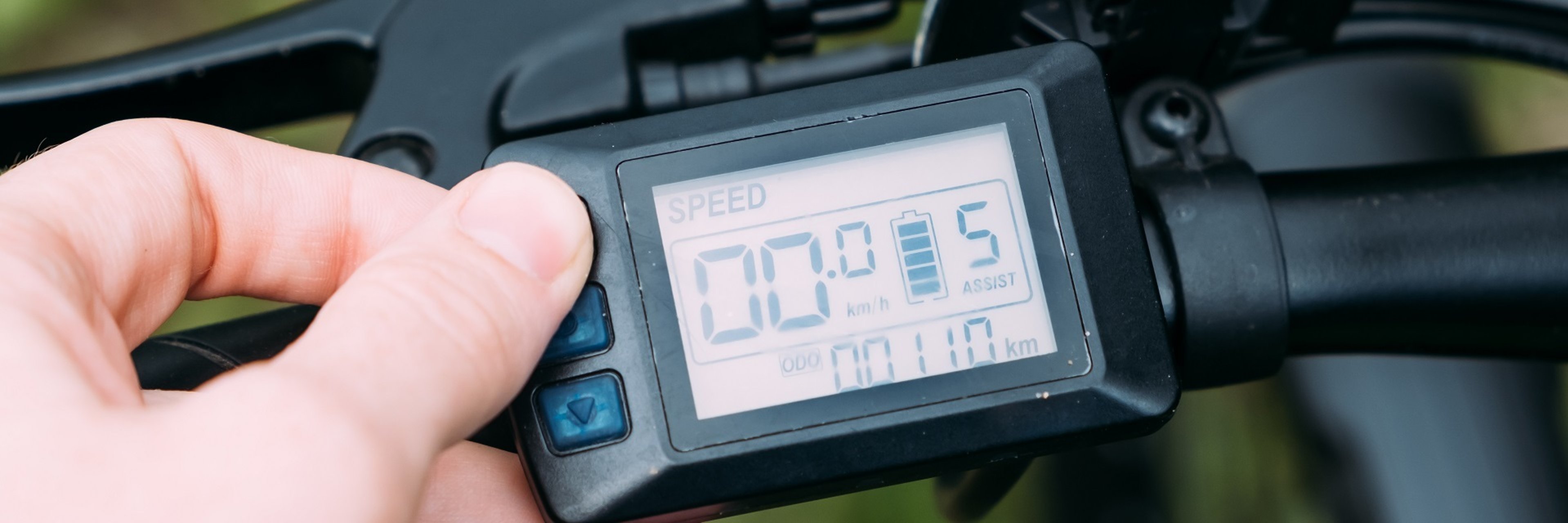Eine Hand programmiert gerade den digitalen Tacho eines E-Bikes.