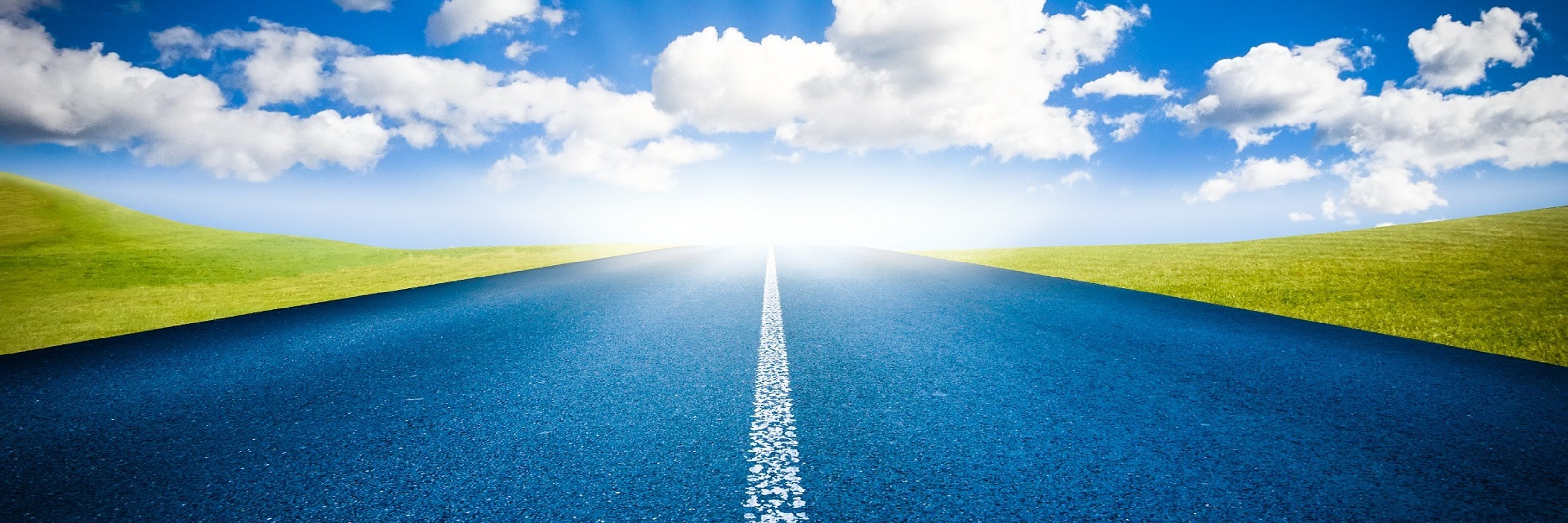 Straße mit Wolkenhimmel und Sonnenstrahlen