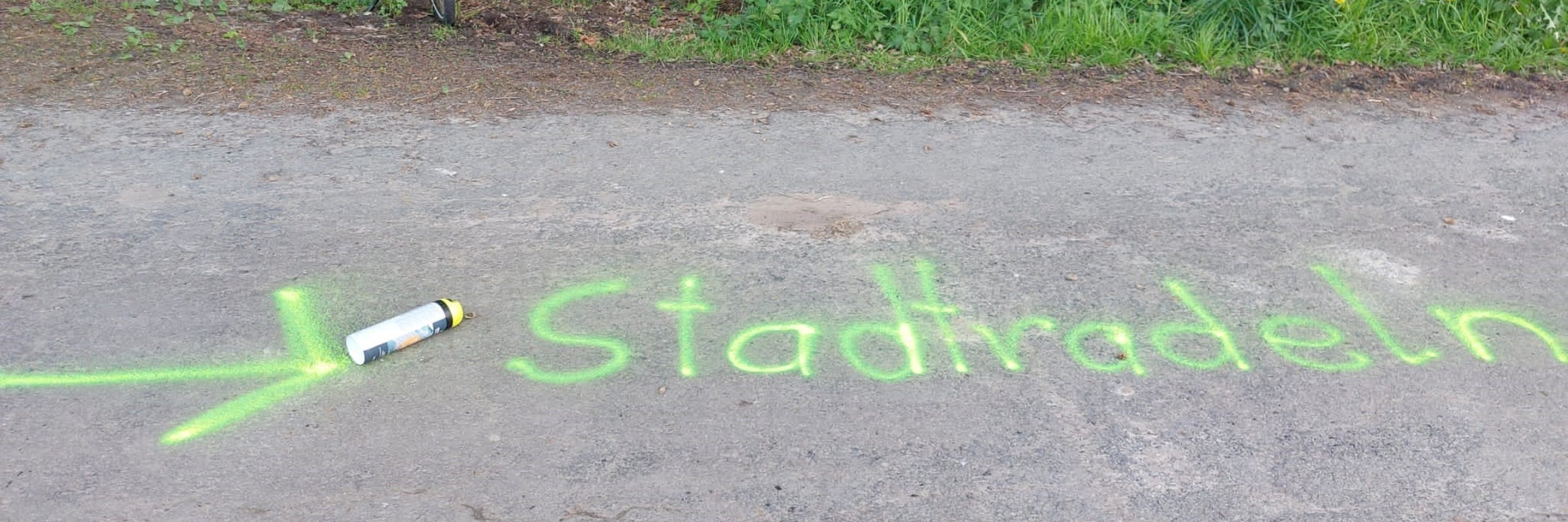 SR-Markierungen Auf einer Straße steht, mit grüner Farbe gesprüht, das Wort Stadtradeln.