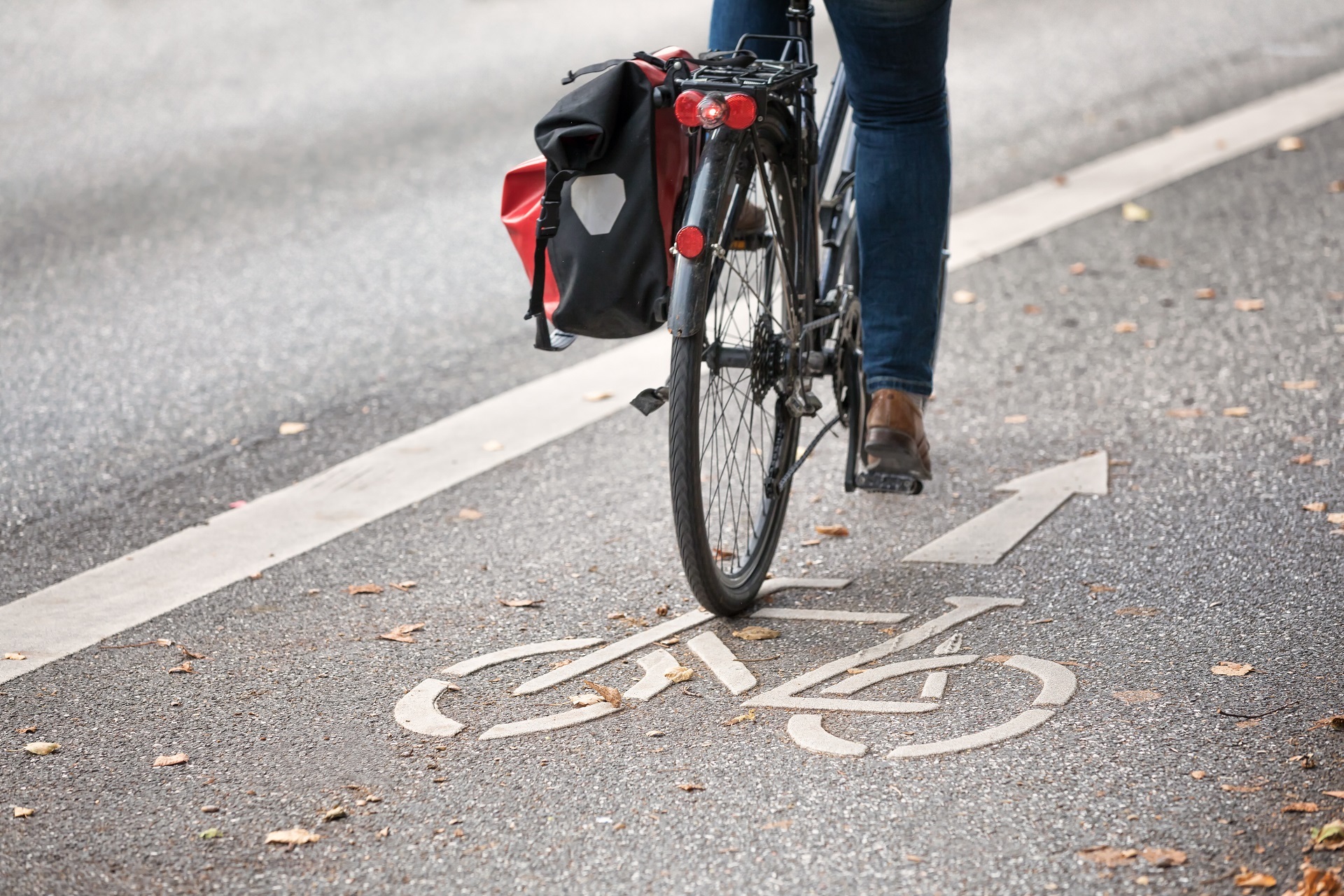 Fahrrad mit Packtasche Ein Fahrrad mit einer schwarz-roten Satteltasche fährt auf einem, von einer Straße abgetrennten Radfahrstreifen.