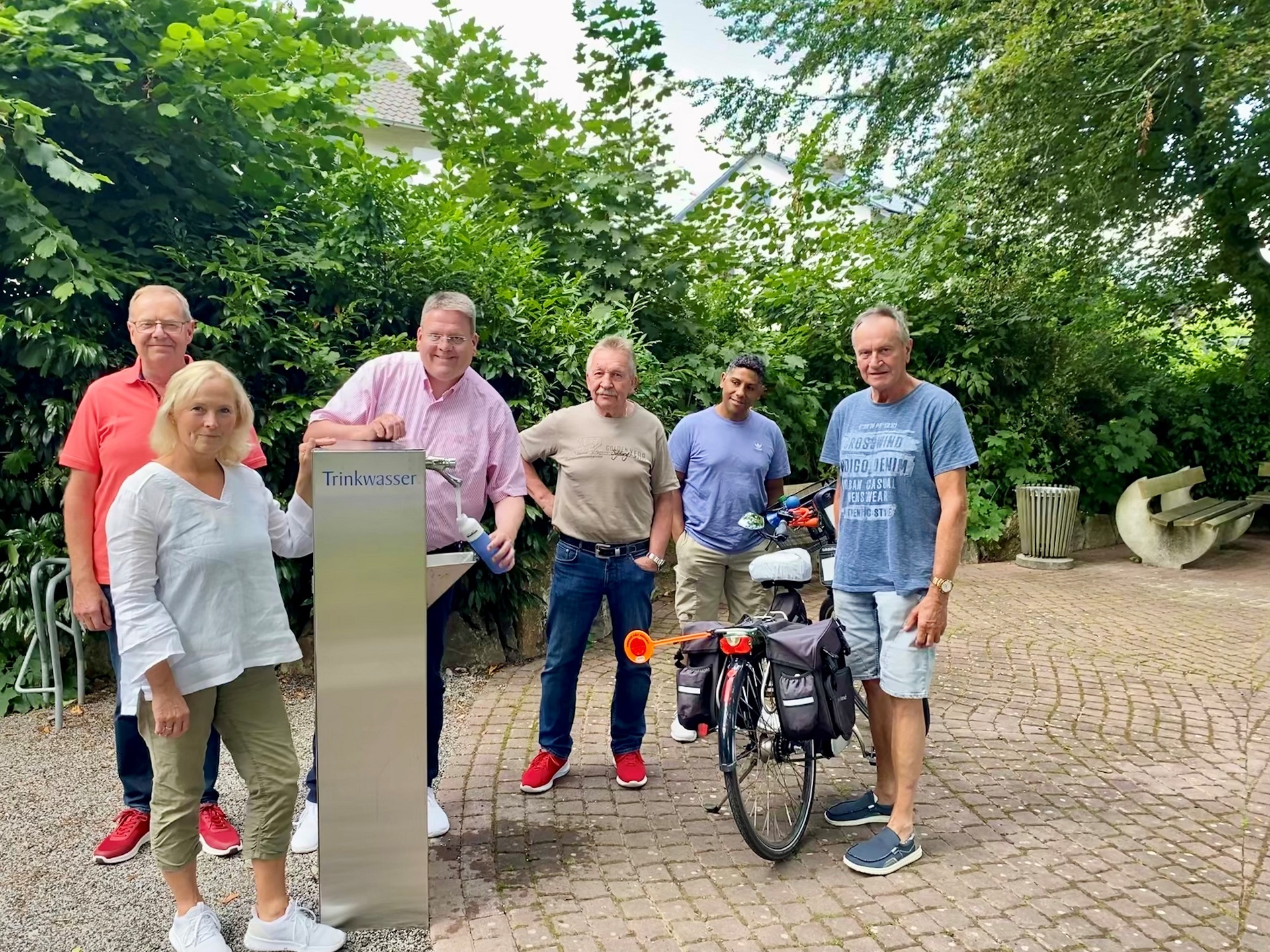 Eine Gruppe Menschen steht an einem Trinkwasserspender.