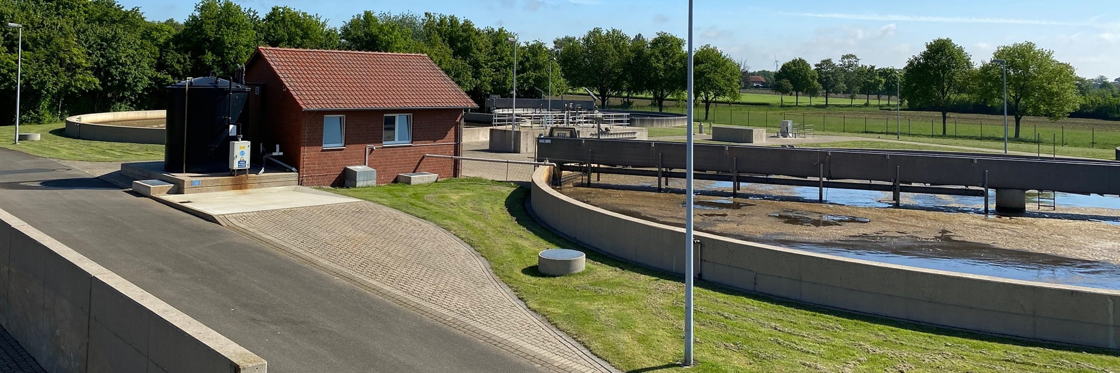 Blick auf verschiedene Klärbecken und eine Pumpenhäuschen einer Kläranlage.