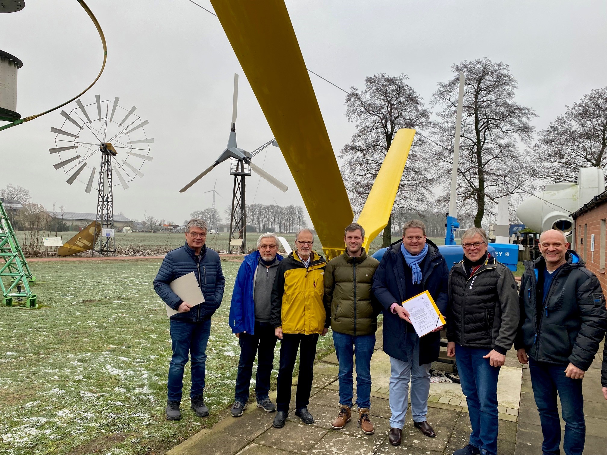 Gruppenfoto mit sieben Männern auf dem Gelände des Deutschen Windkraftmuseums.
