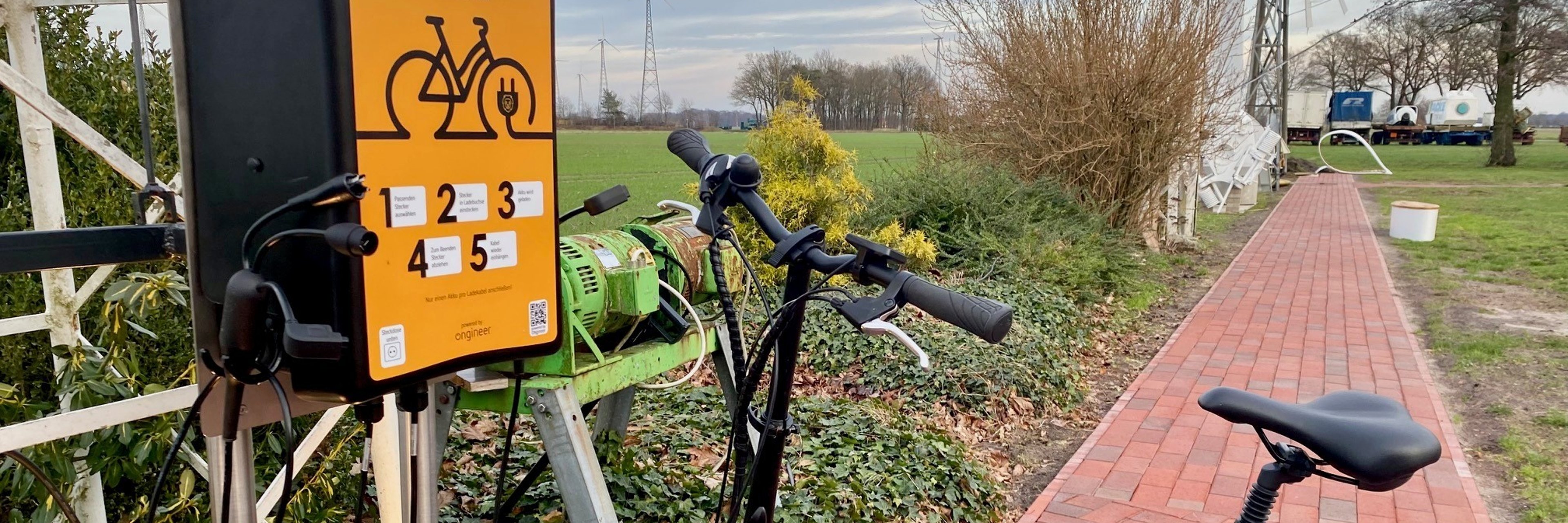 Eine orange-farbene Ladesäule für E-Bikes. 