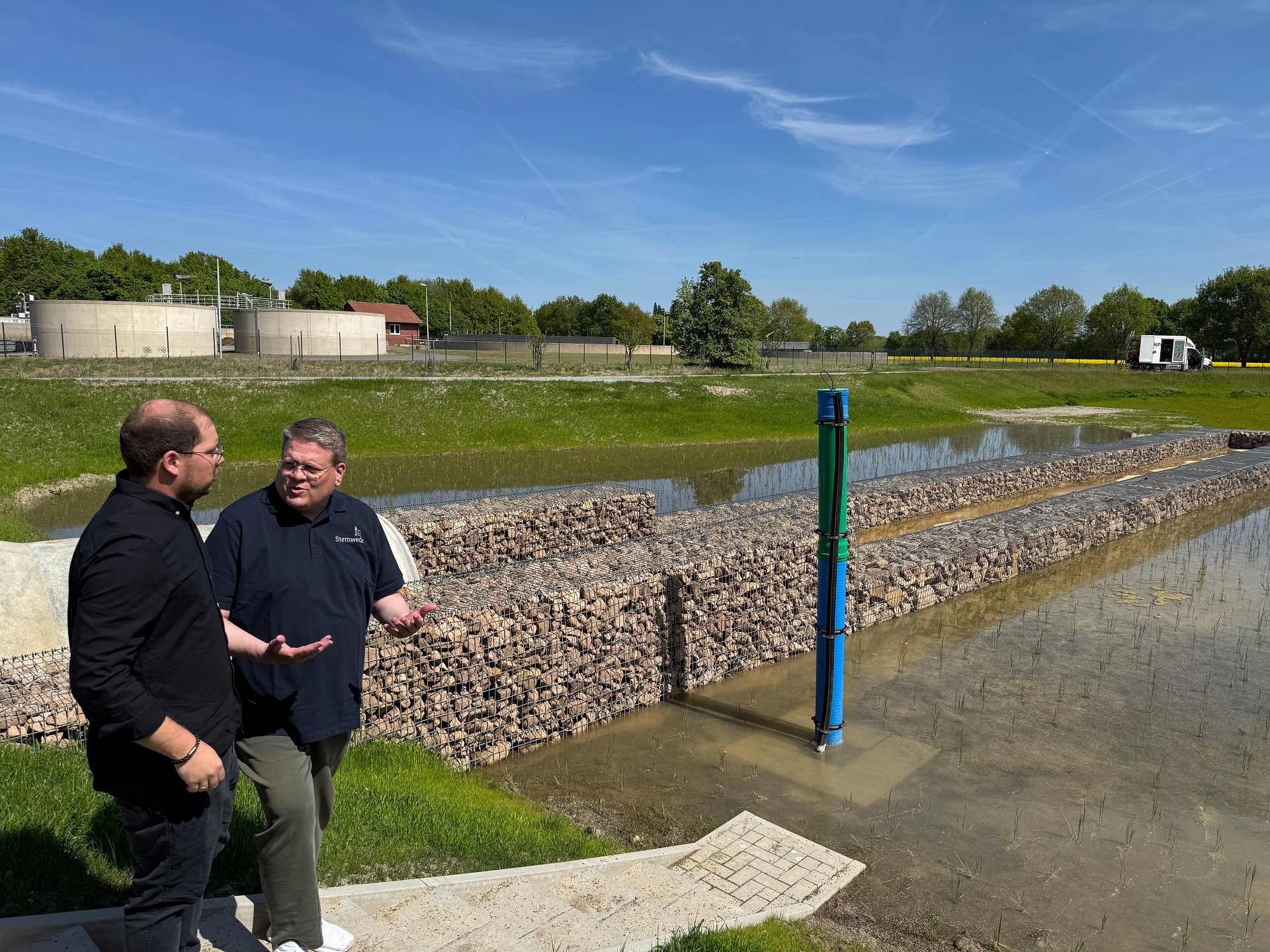 Filter an der Kläranlage Zwei Männer stehen an einem künstlich angelegten Teich der als Filter an einer Kläranlage dient.