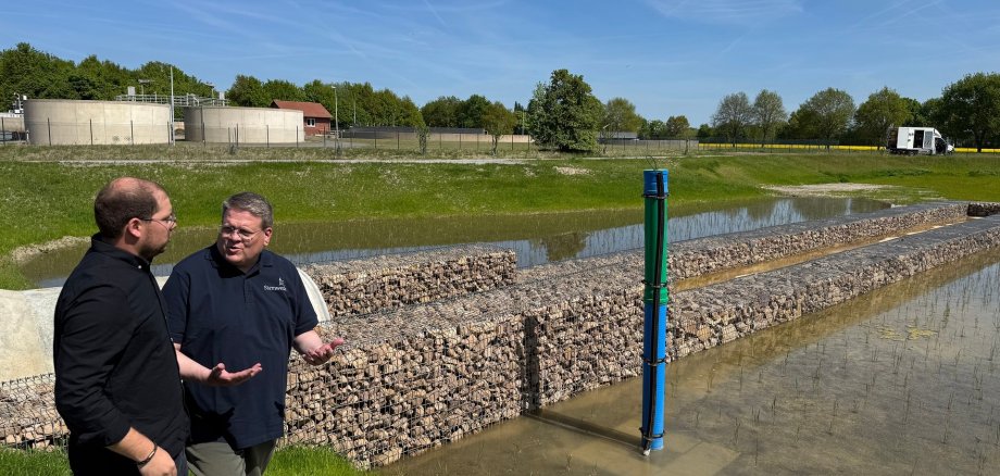 Zwei Männer stehen an einem künstlich angelegten Teich der als Filter an einer Kläranlage dient.