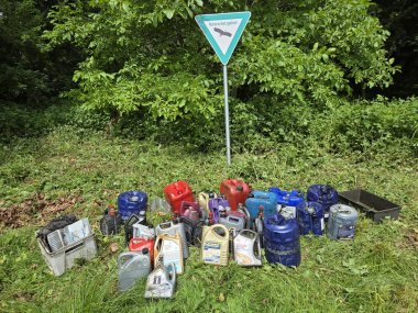Altölbehälter im Stemweder Berg Mehrere Dutzend Altölkanister und Ölbehälter stehen auf einer freigeschnittenen Fläche am Waldrand unter einem Schild mit der Aufschrift „Naturschutzgebiet“. Die unterschiedlich großen Behälter in Blau, Rot, Grau und Beige wurden zuvor illegal in der Natur entsorgt und für die Bergung zusammengetragen. Im Hintergrund ist dichter Bewuchs mit Bäumen und Sträuchern zu sehen. Die Aufnahme verdeutlicht das Ausmaß der unerlaubten Müllablagerung in einem geschützten Naturbereich.